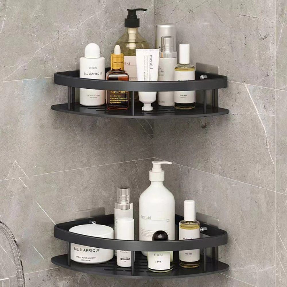 Étagère de douche incurvée en aluminium noir à deux niveaux contenant des produits de bain et de soin sur un mur carrelé gris