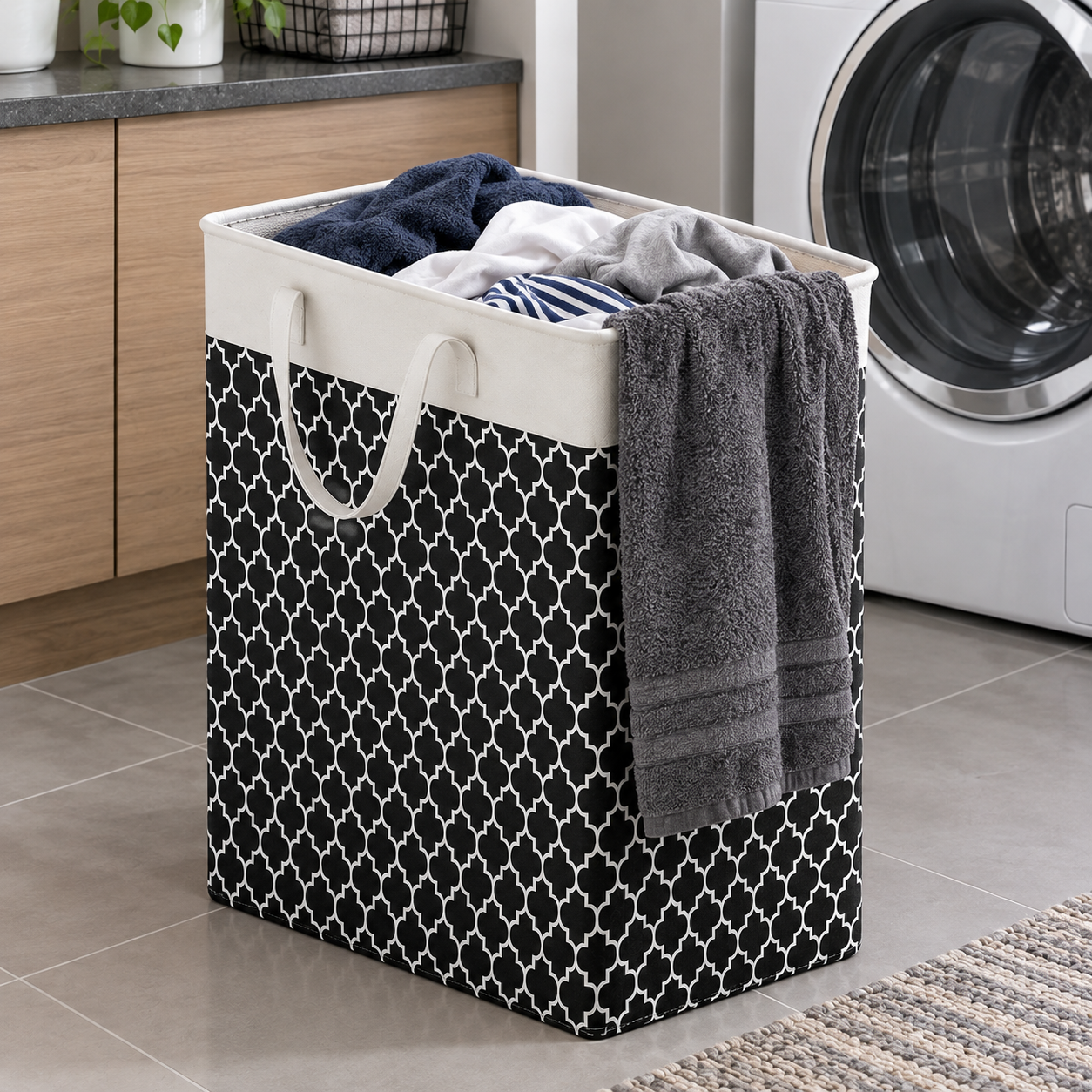 Panier à linge à motif géométrique noir et blanc avec doublure en toile crème rempli de vêtements pliés